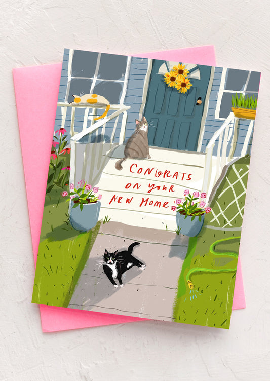 An illustrated greeting card with cats sitting on stoop, text reads "Congrats on your new home".
