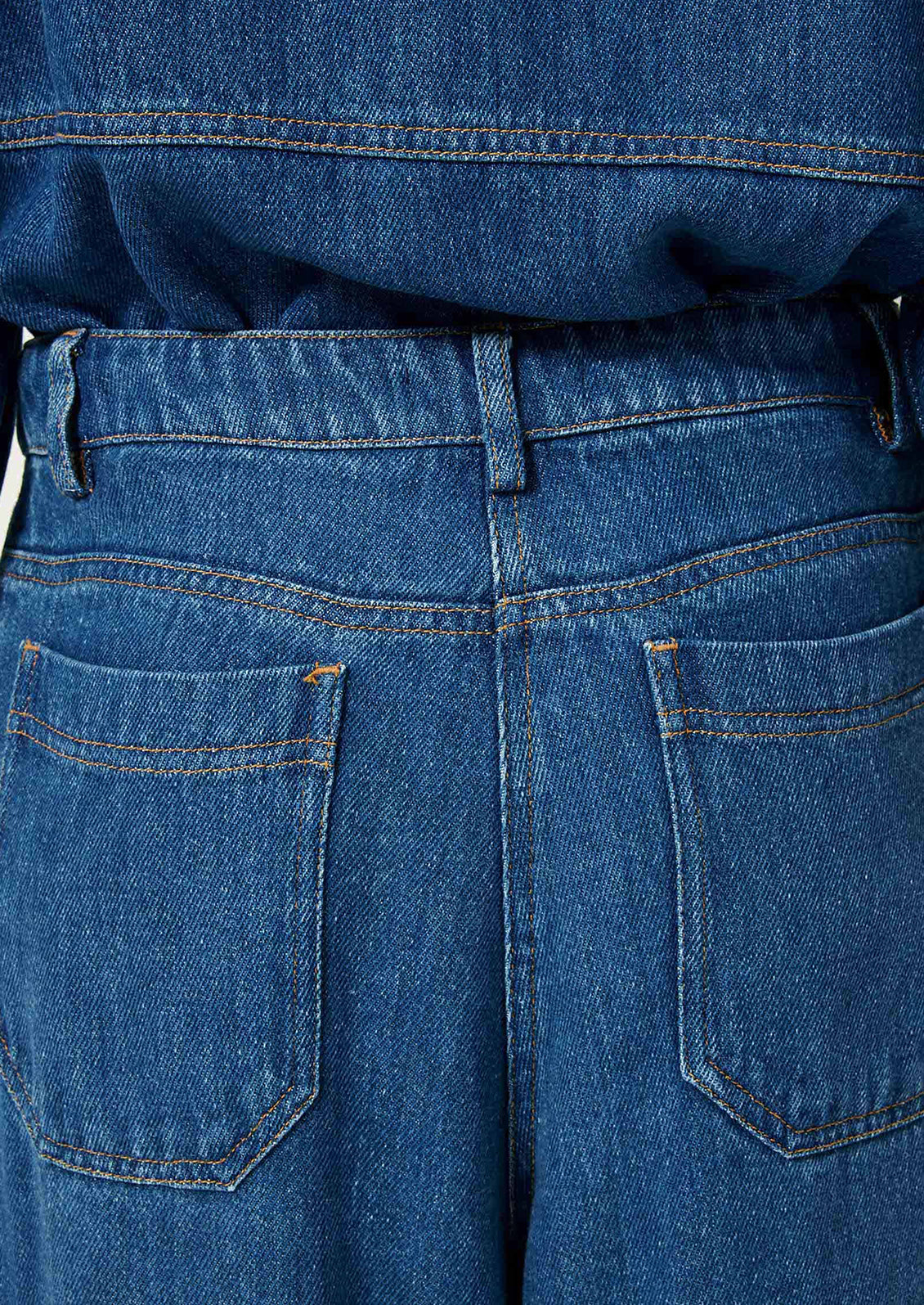 A woman wearing a denim jacket and pants in rich blue denim.
