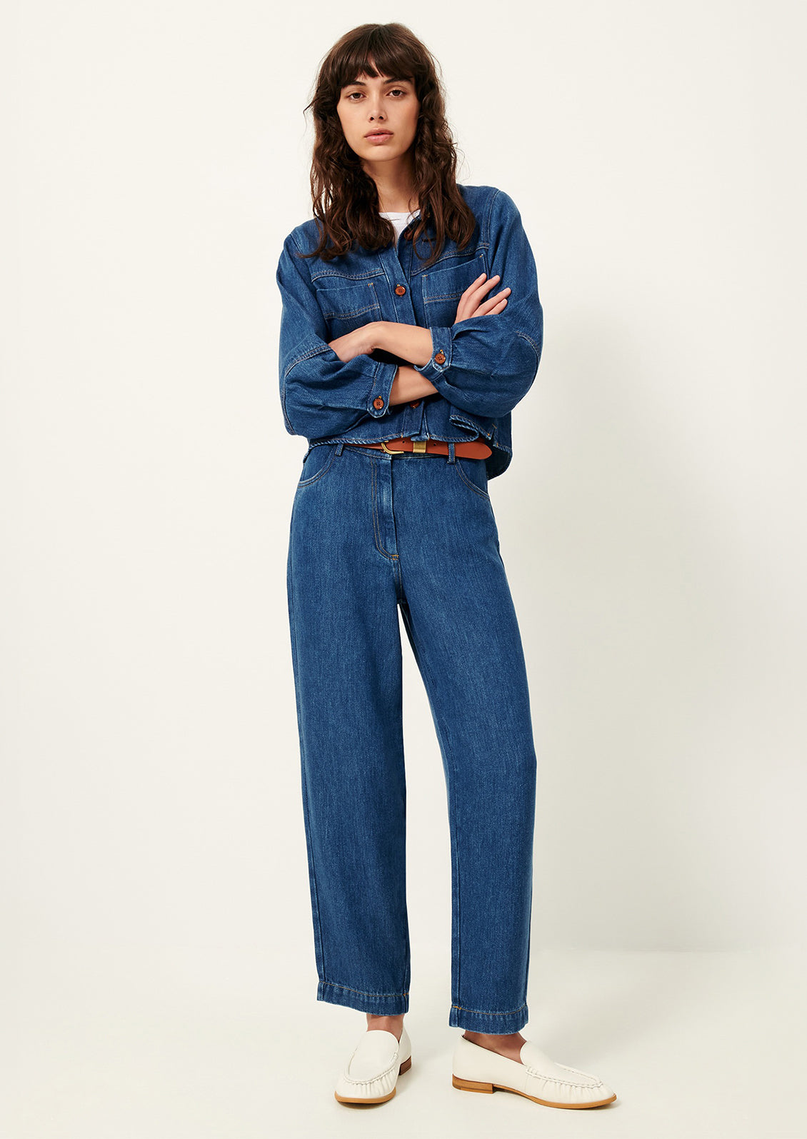 A woman wearing a denim jacket and pants in rich blue denim.