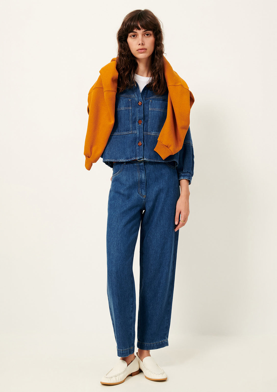 A woman wearing a denim jacket and pants in rich blue denim.