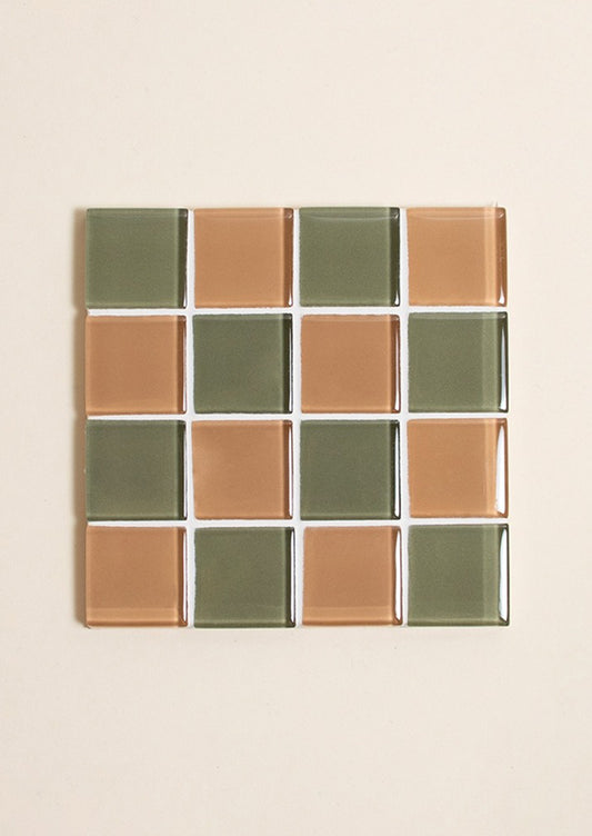 A glass tile coaster in two tone checker pattern in olive green and chocolate brown.