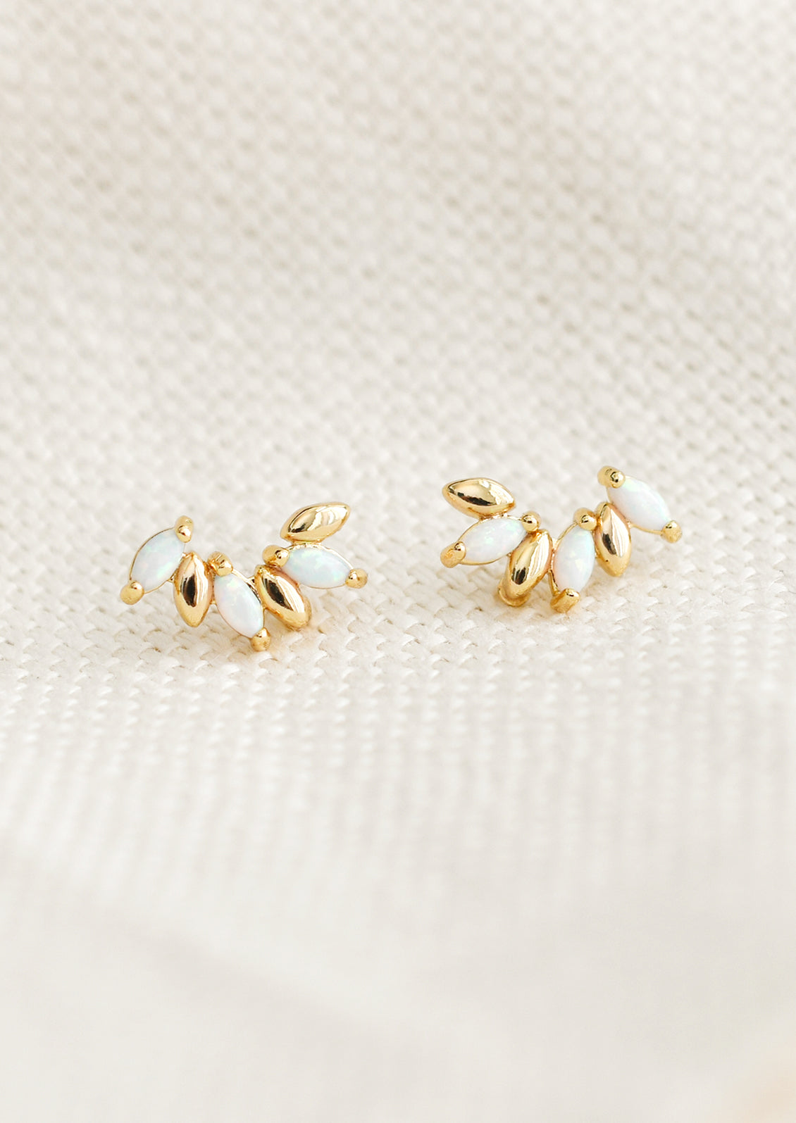A pair of gold studs with seed like shape, with opal accents.