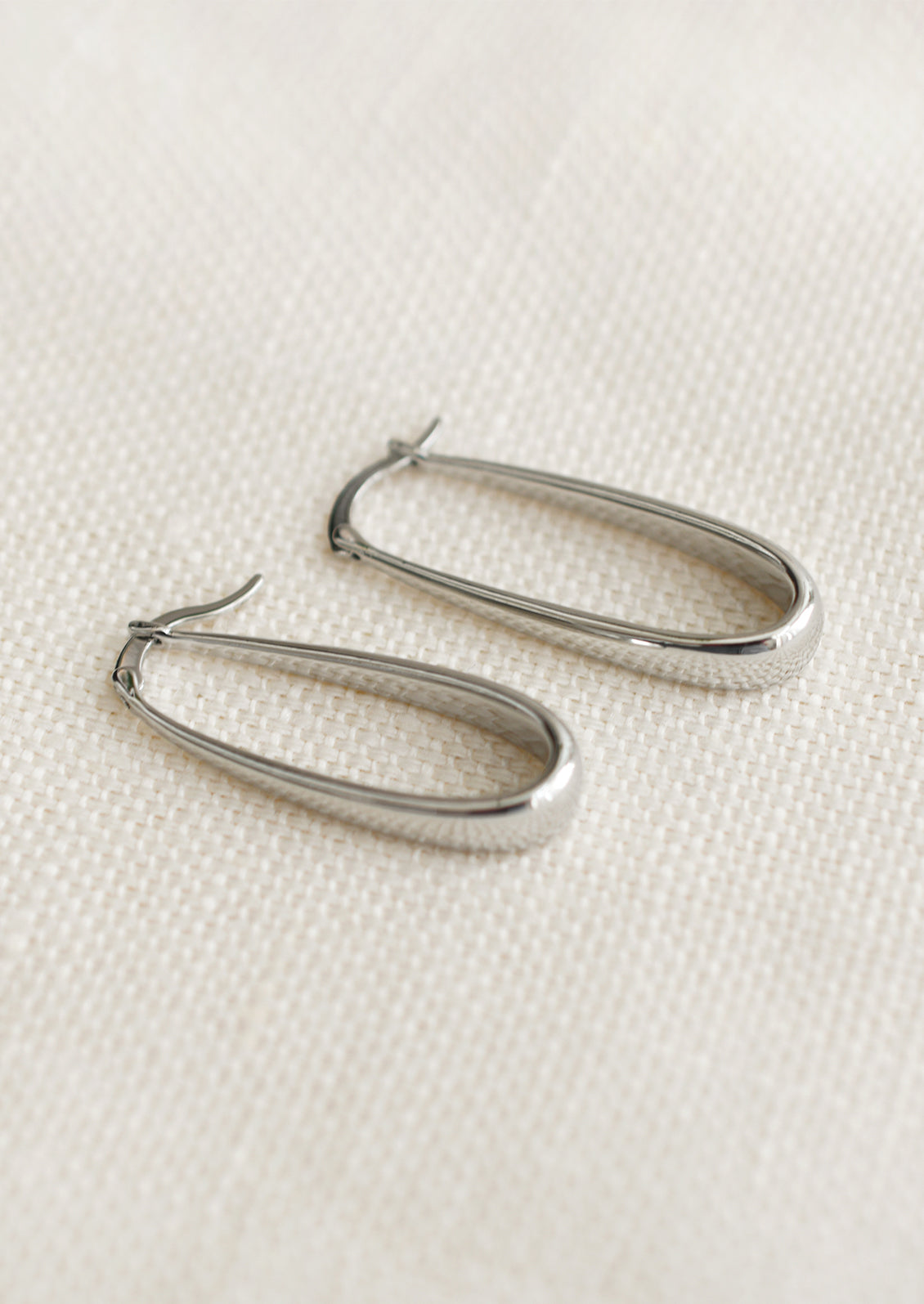 A pair of oblong hoop earrings with subtly tapered thickness, in silver.