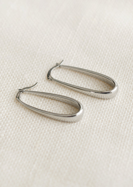 A pair of oblong hoop earrings with subtly tapered thickness, in silver.