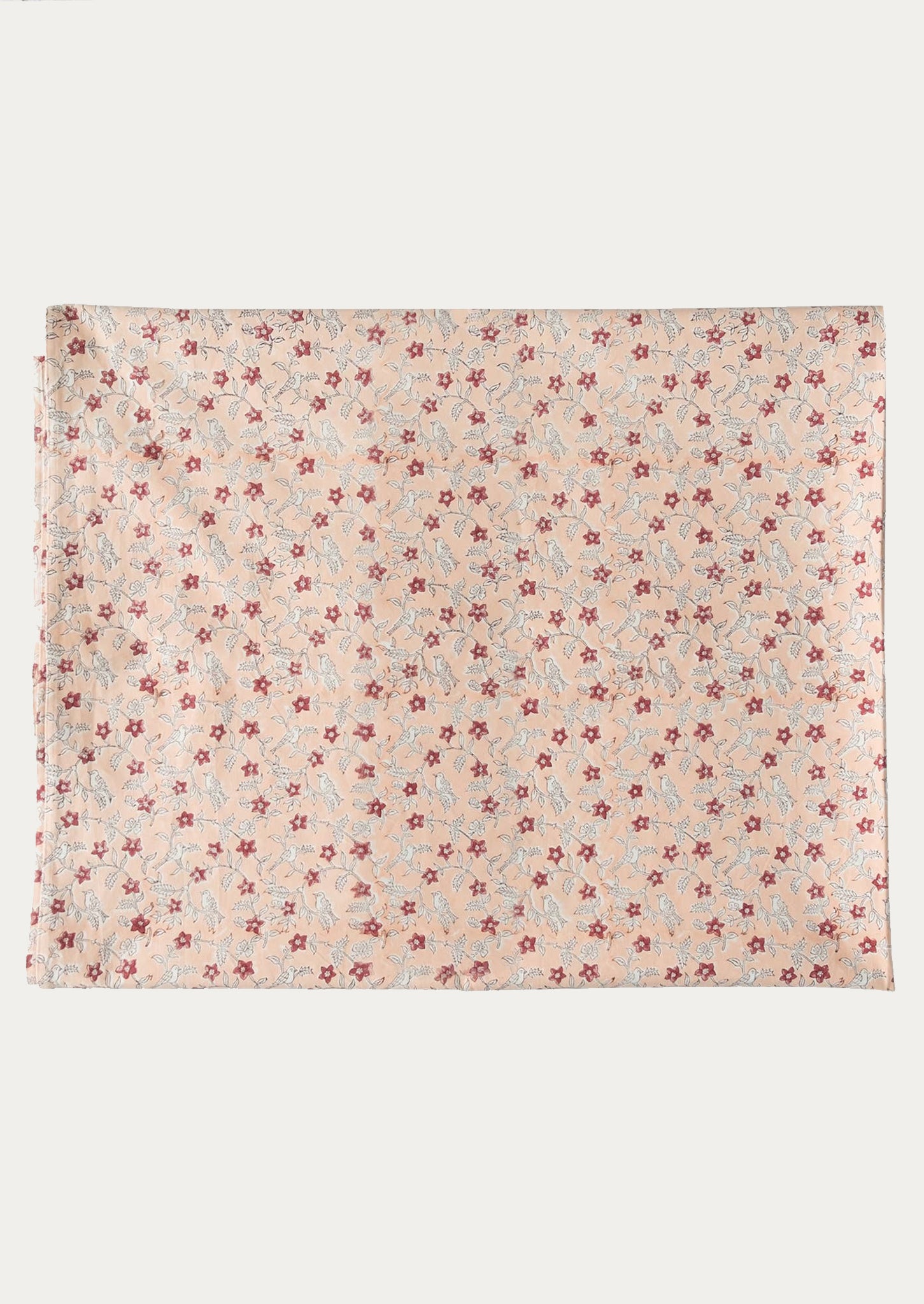 A folded tablecloth in peach floral pattern.
