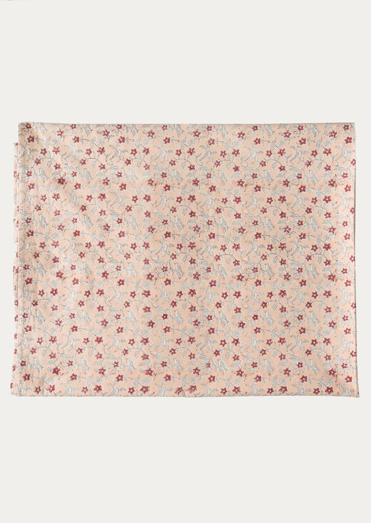 A folded tablecloth in peach floral pattern.