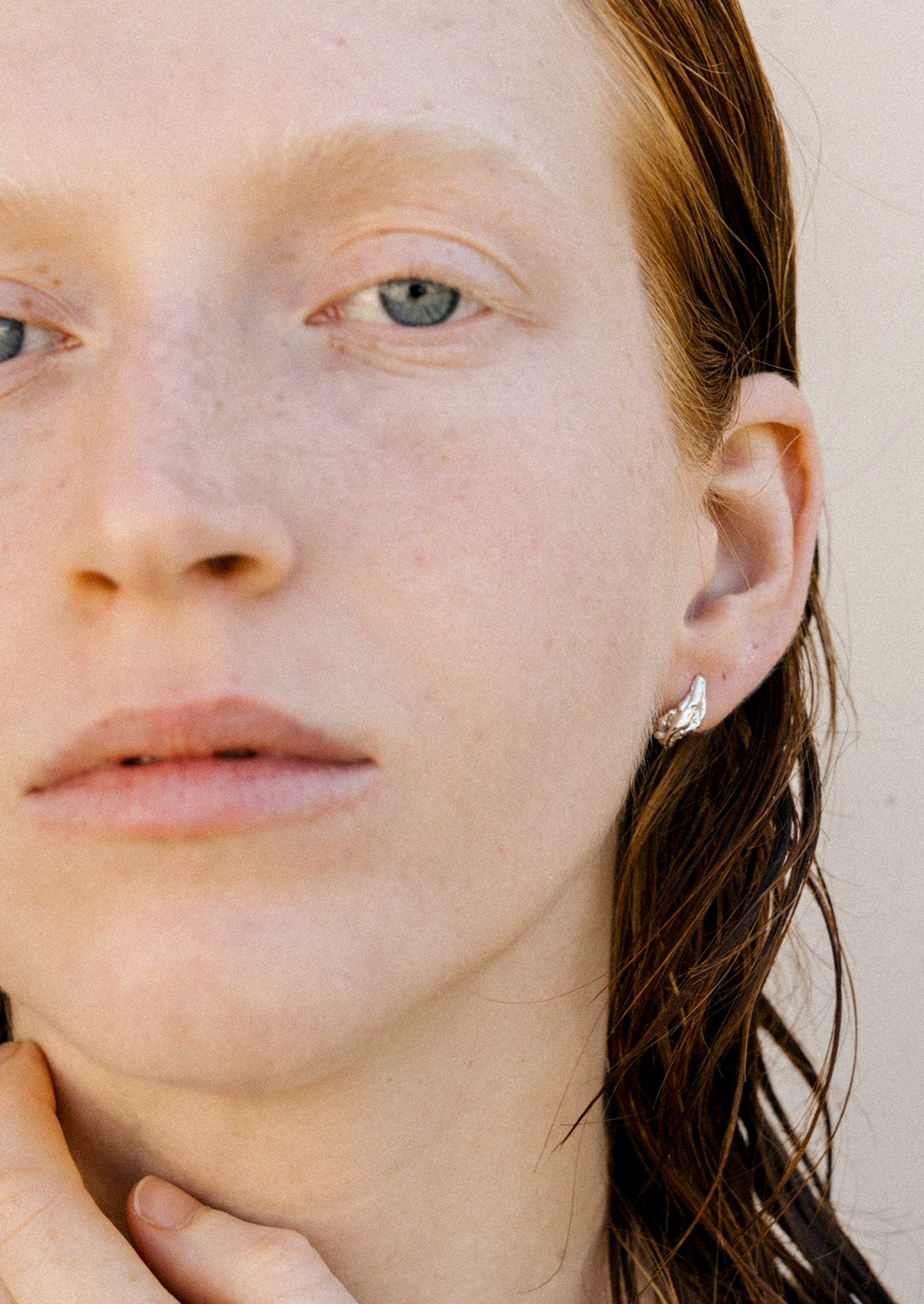 A woman wearing a sterling silver earring in an abstract shape.