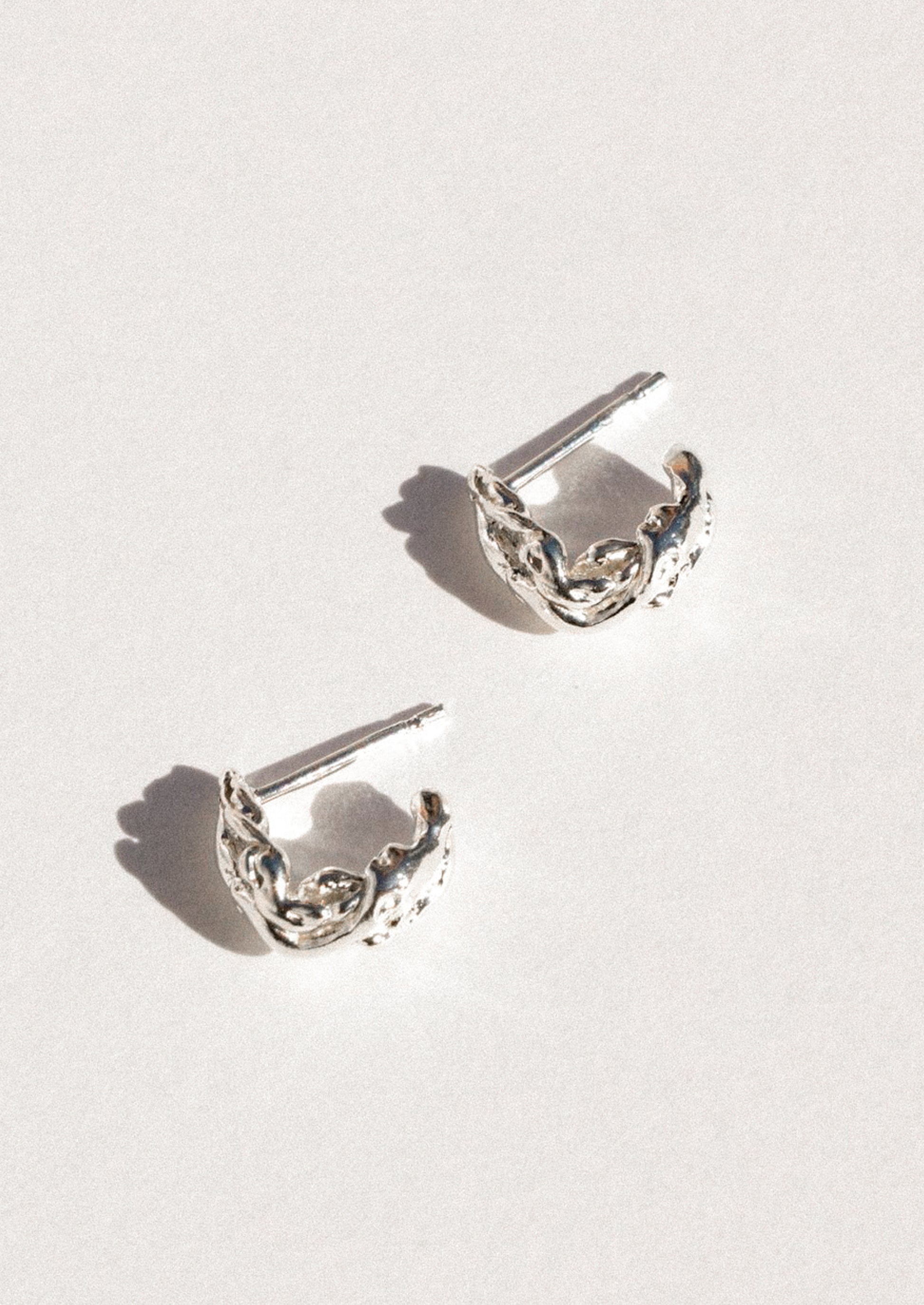 A pair of sterling silver earrings in an abstract shape.