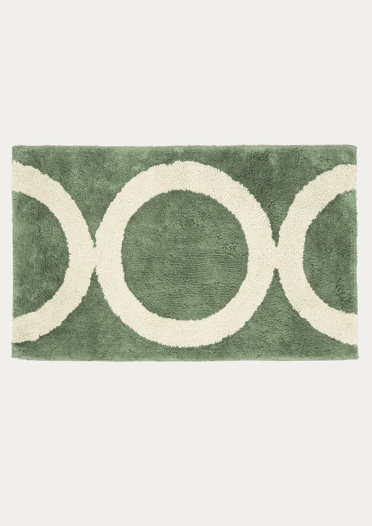 Green rug with white circular patterns on a white background