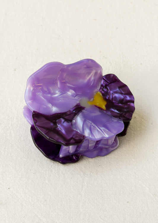 A hair claw depicting a purple pansy flower.