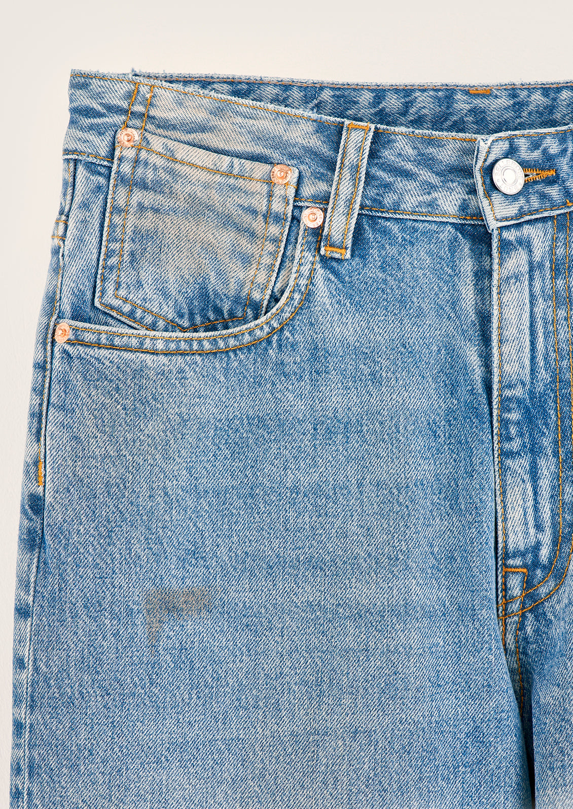 A pair of wide leg jeans in medium blue wash with dirt and paint marks.