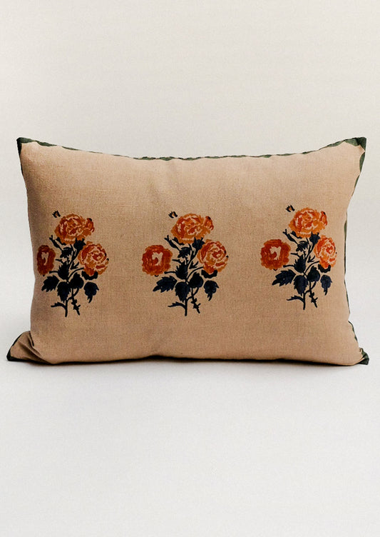 Beige pillow with rust colored floral print and scalloped green border.