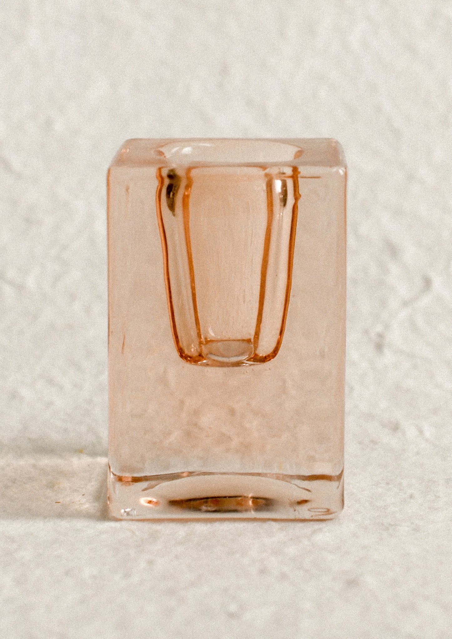A cube-shaped slab glass candleholder in peach / tall.