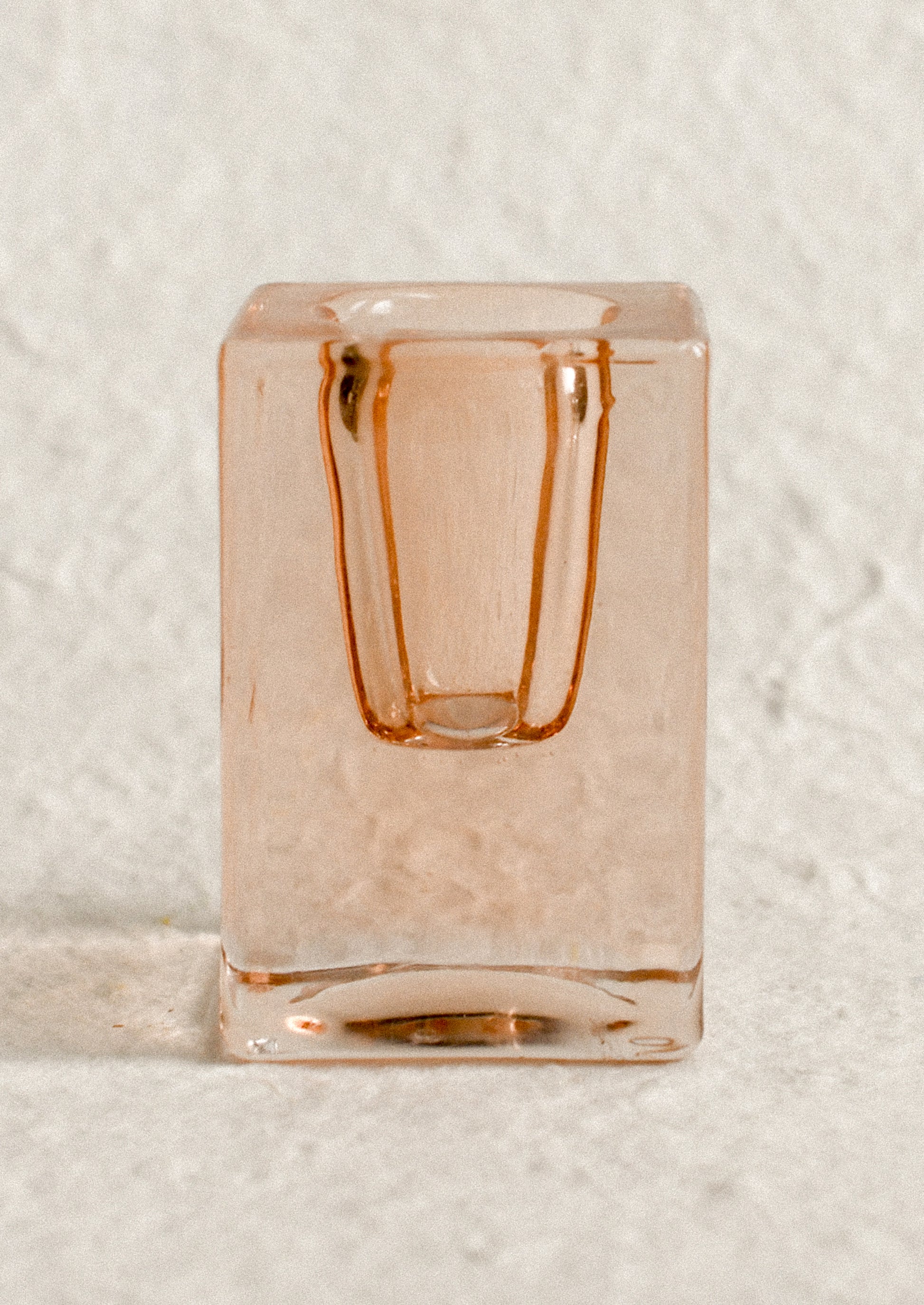 A cube-shaped slab glass candleholder in peach / tall.