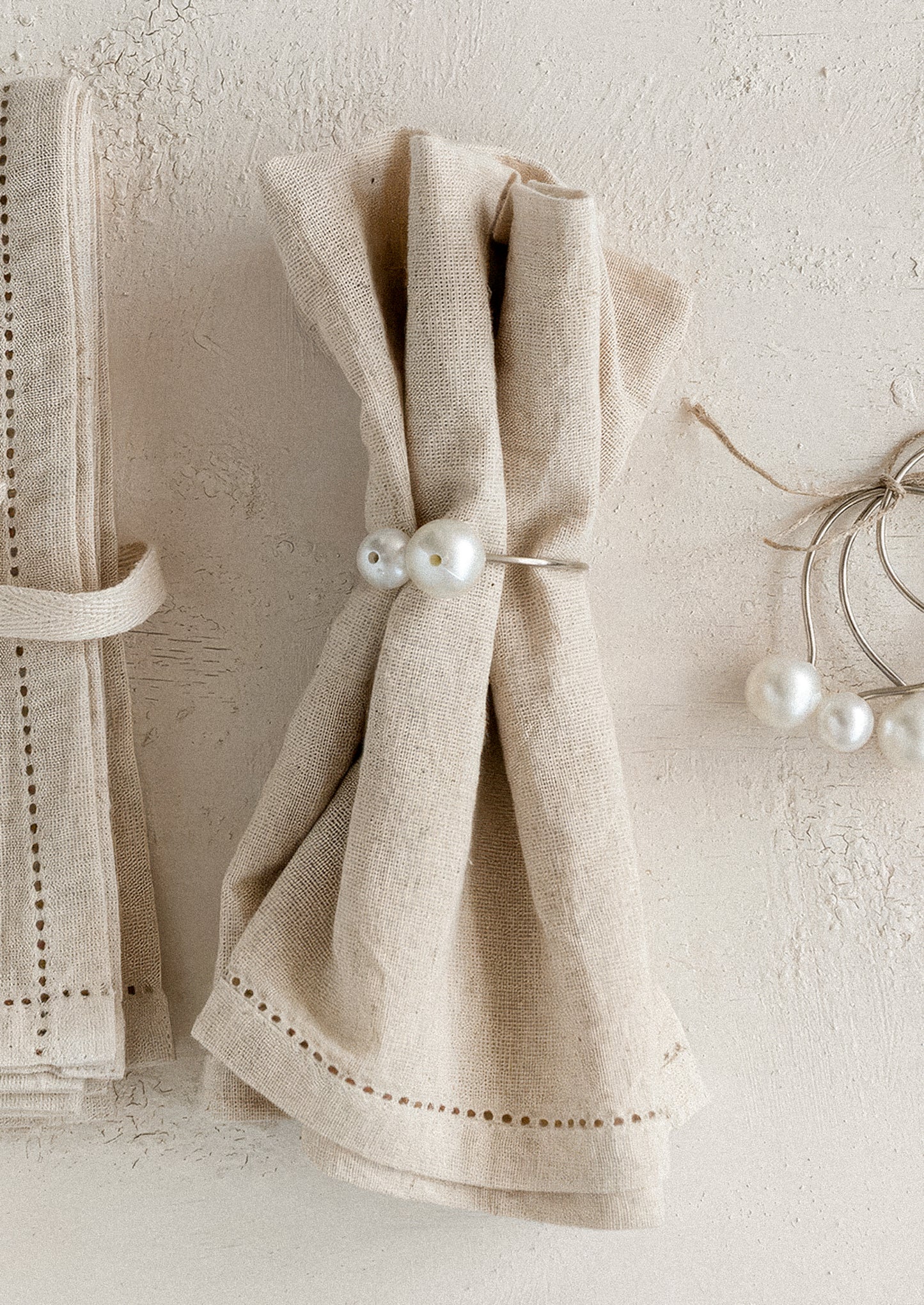 Beige napkin with pearl decorations on a textured white surface