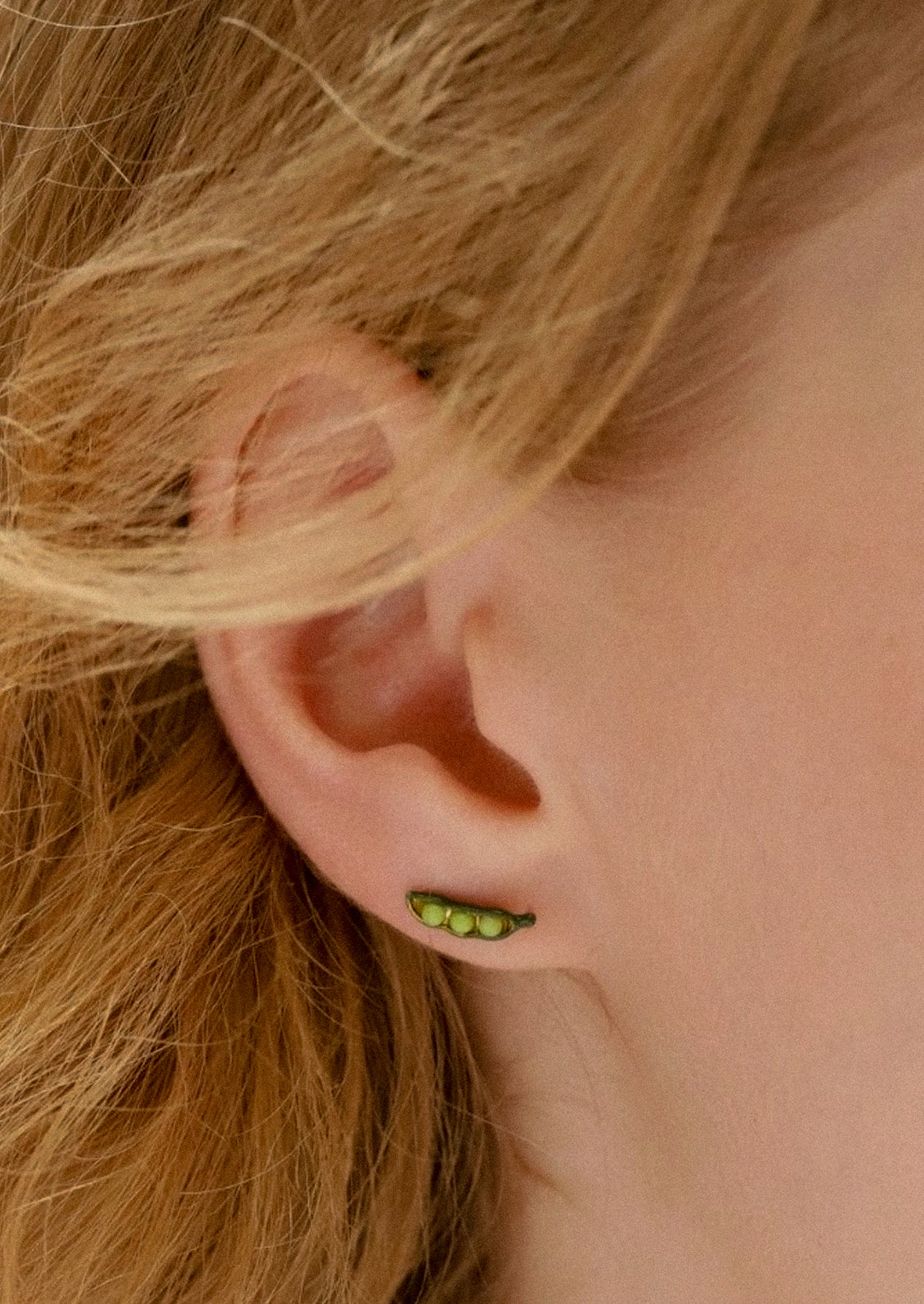 A woman wearing a pea pod earring.