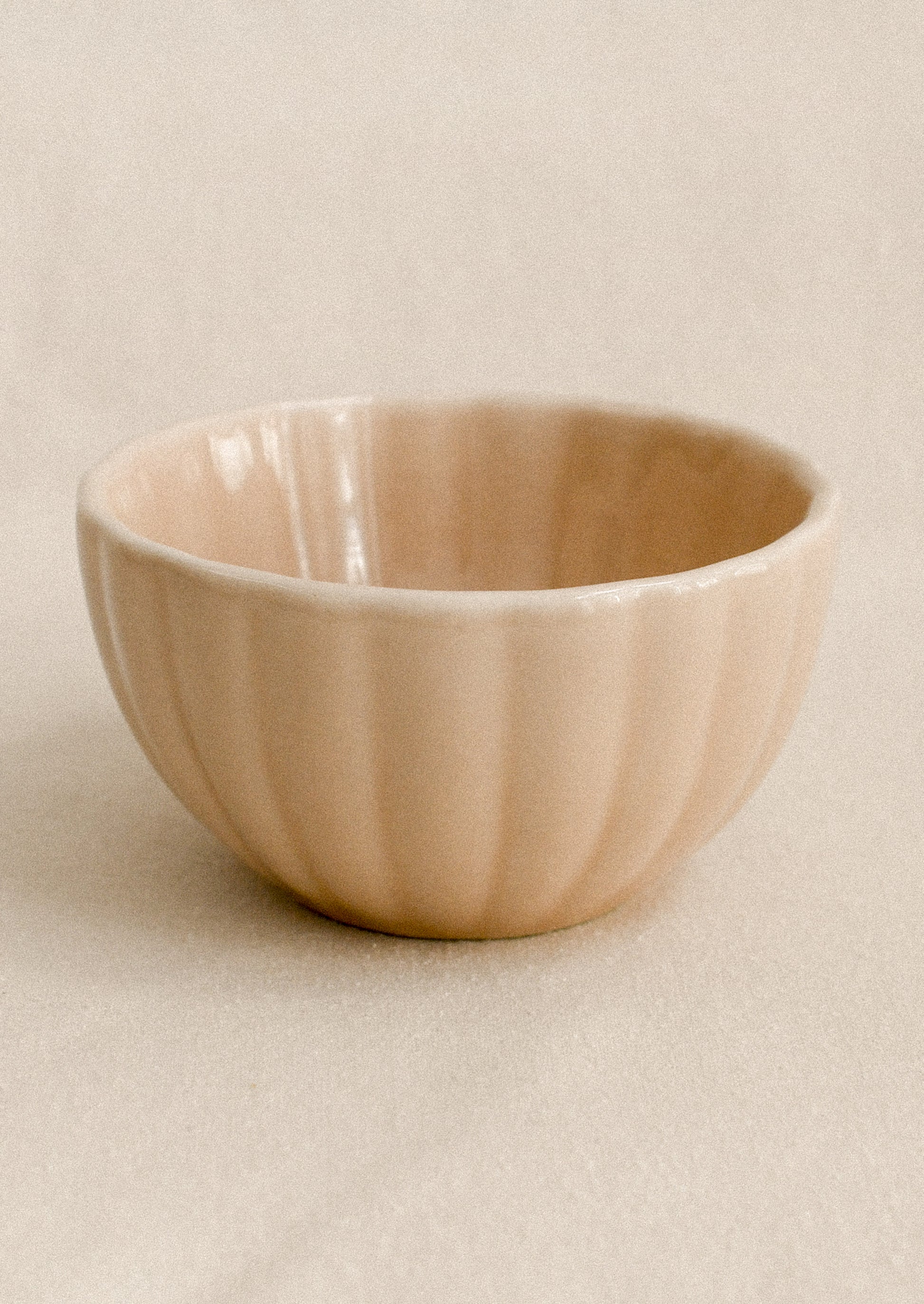 Peach ceramic bowl on a beige background