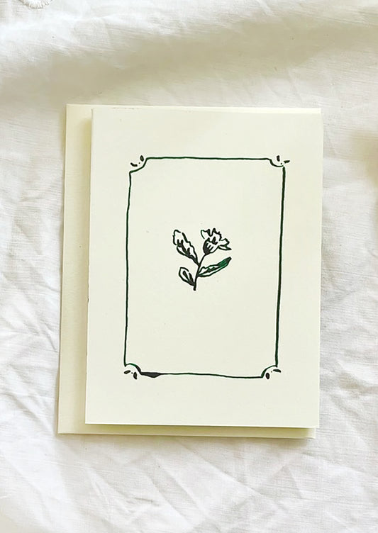 A card with framed floral illustration in green ink.