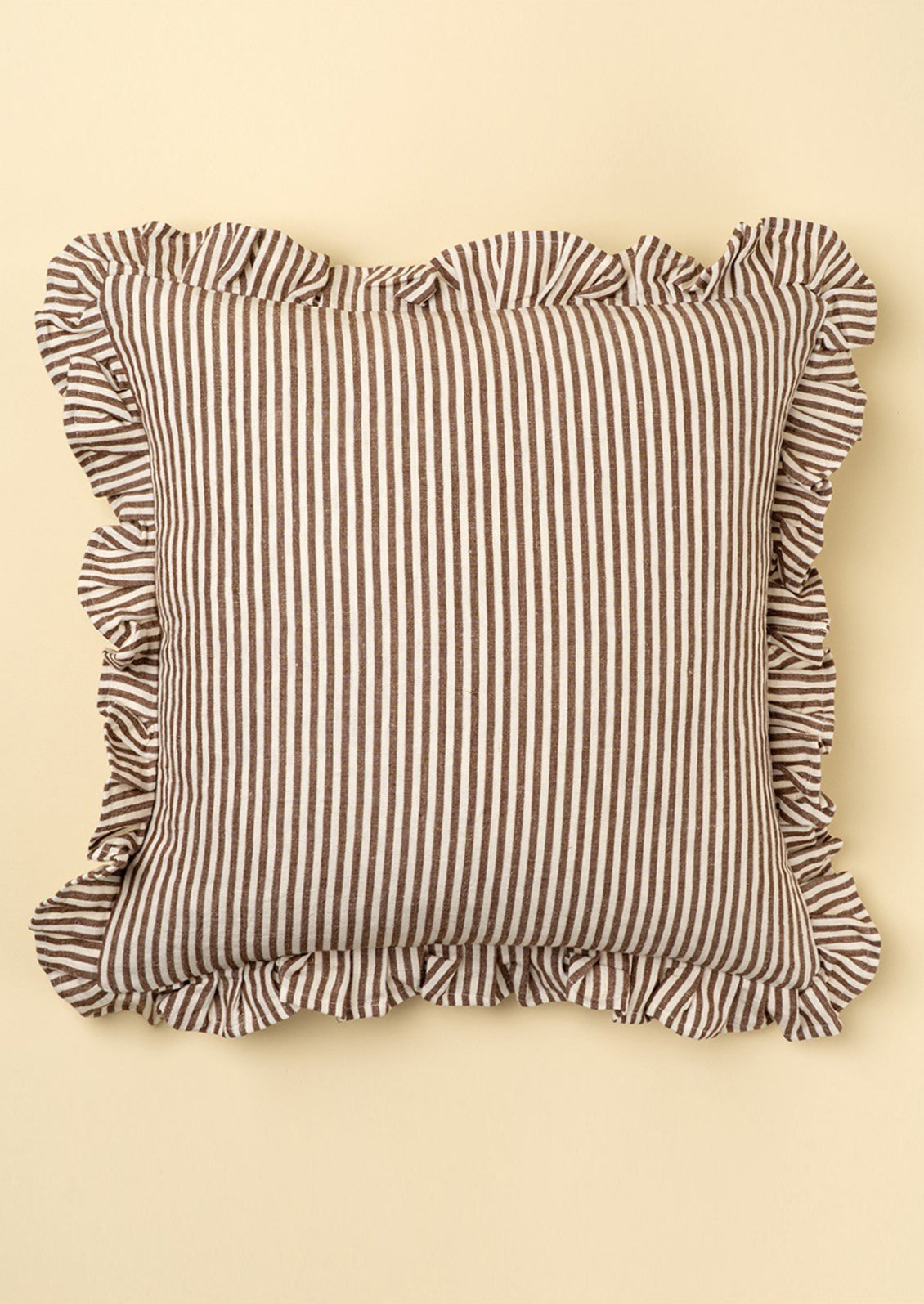 Striped pillow with ruffled edges on a beige background