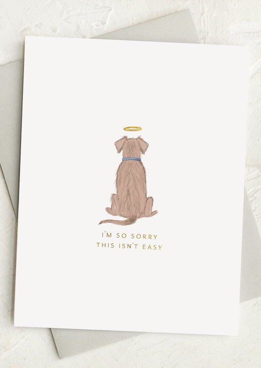 Greeting card with an illustration of a dog wearing a angelic halo and text 'I'm so sorry this isn't easy' on a white background.