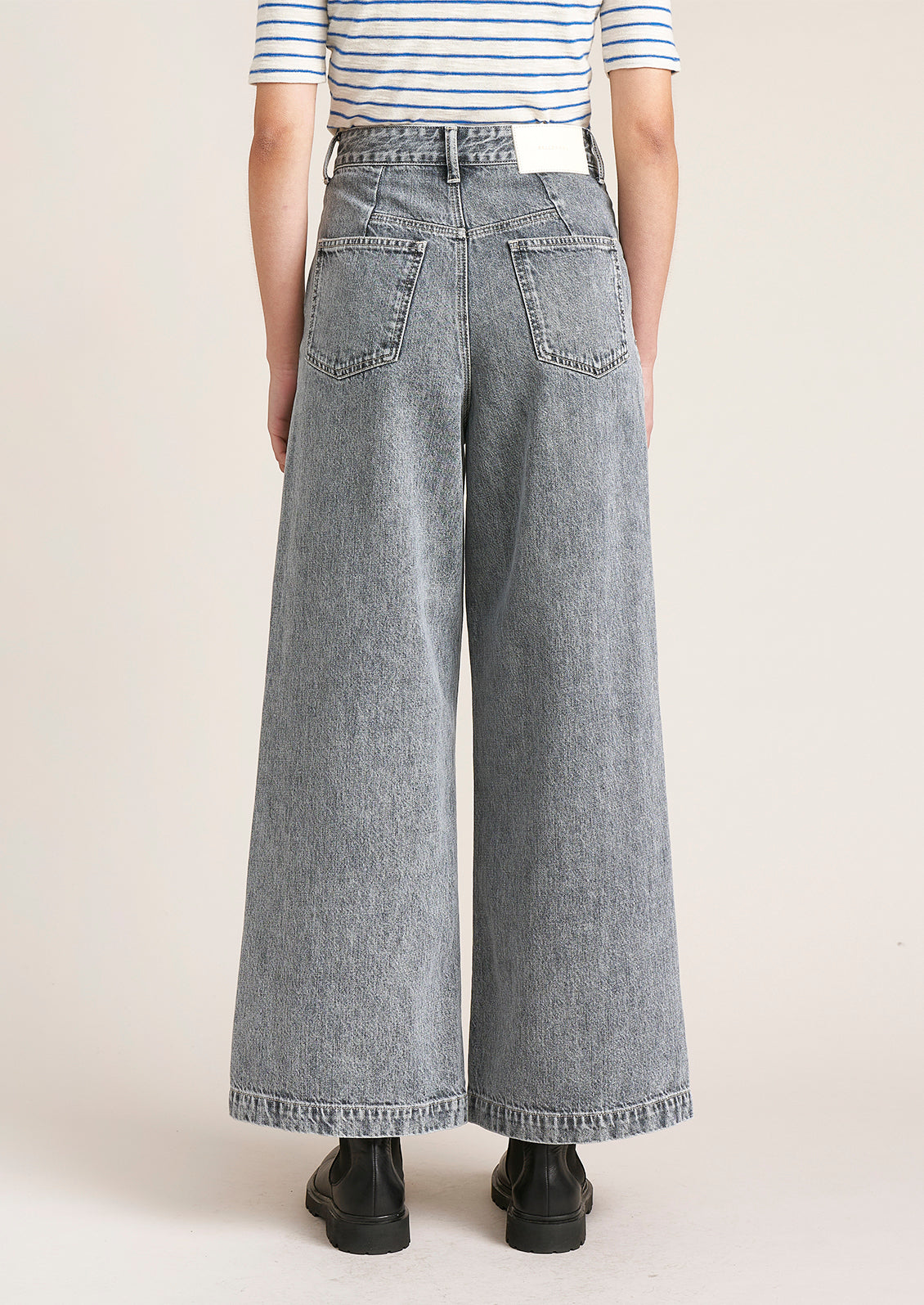 A woman wearing a pair of jeans in stonewashed blue-grey wash with back patch pockets.