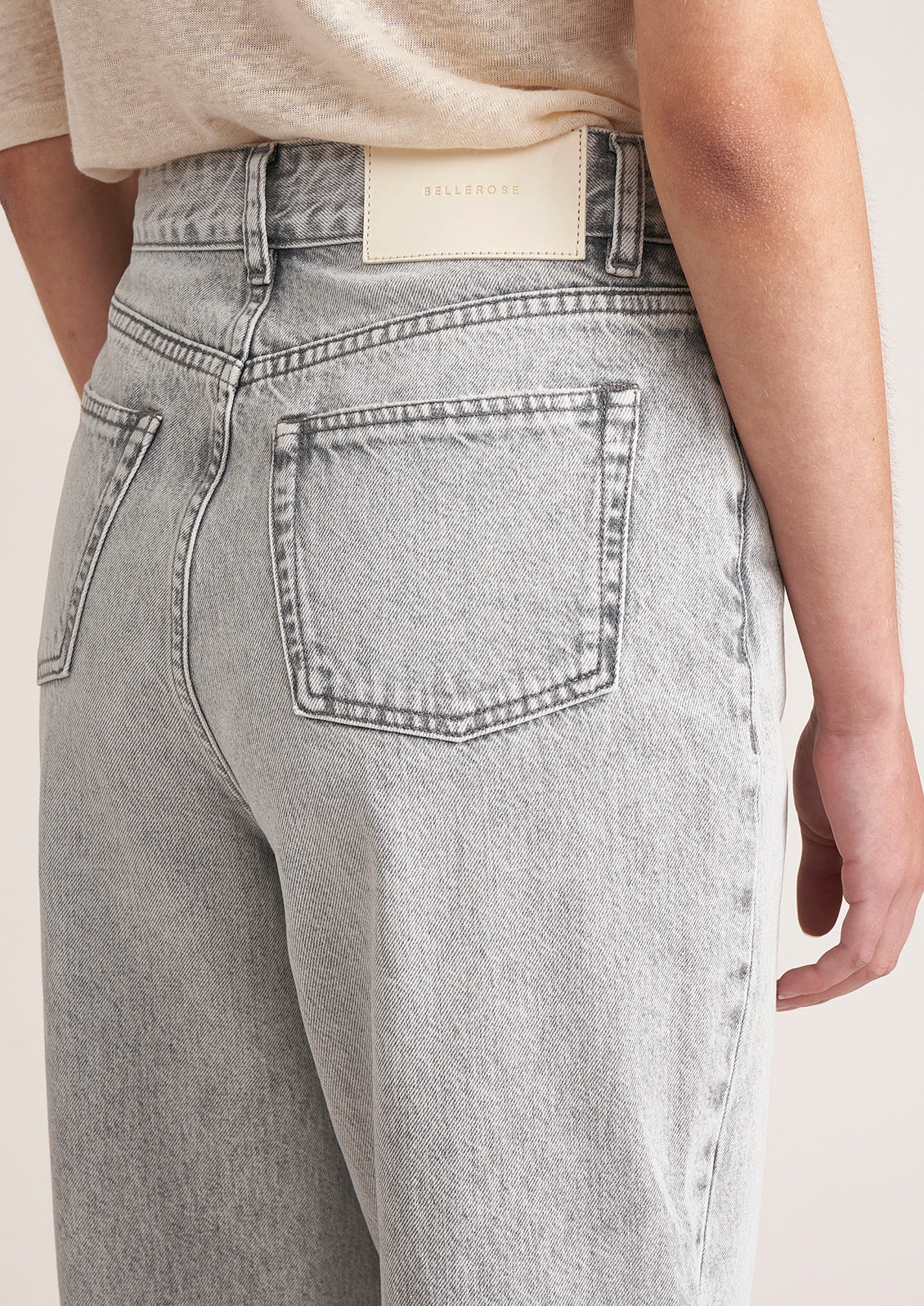 A person wearing a pair of light grey wash tapered leg jeans.