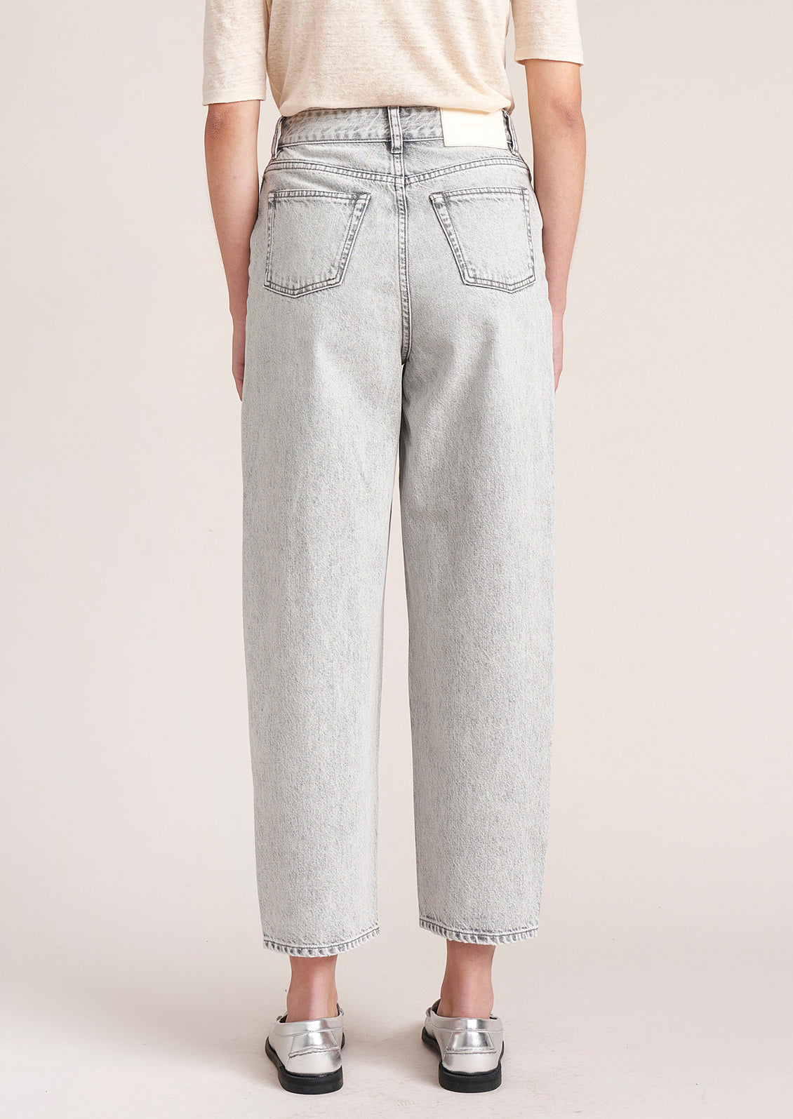 A person wearing a pair of light grey wash tapered leg jeans.