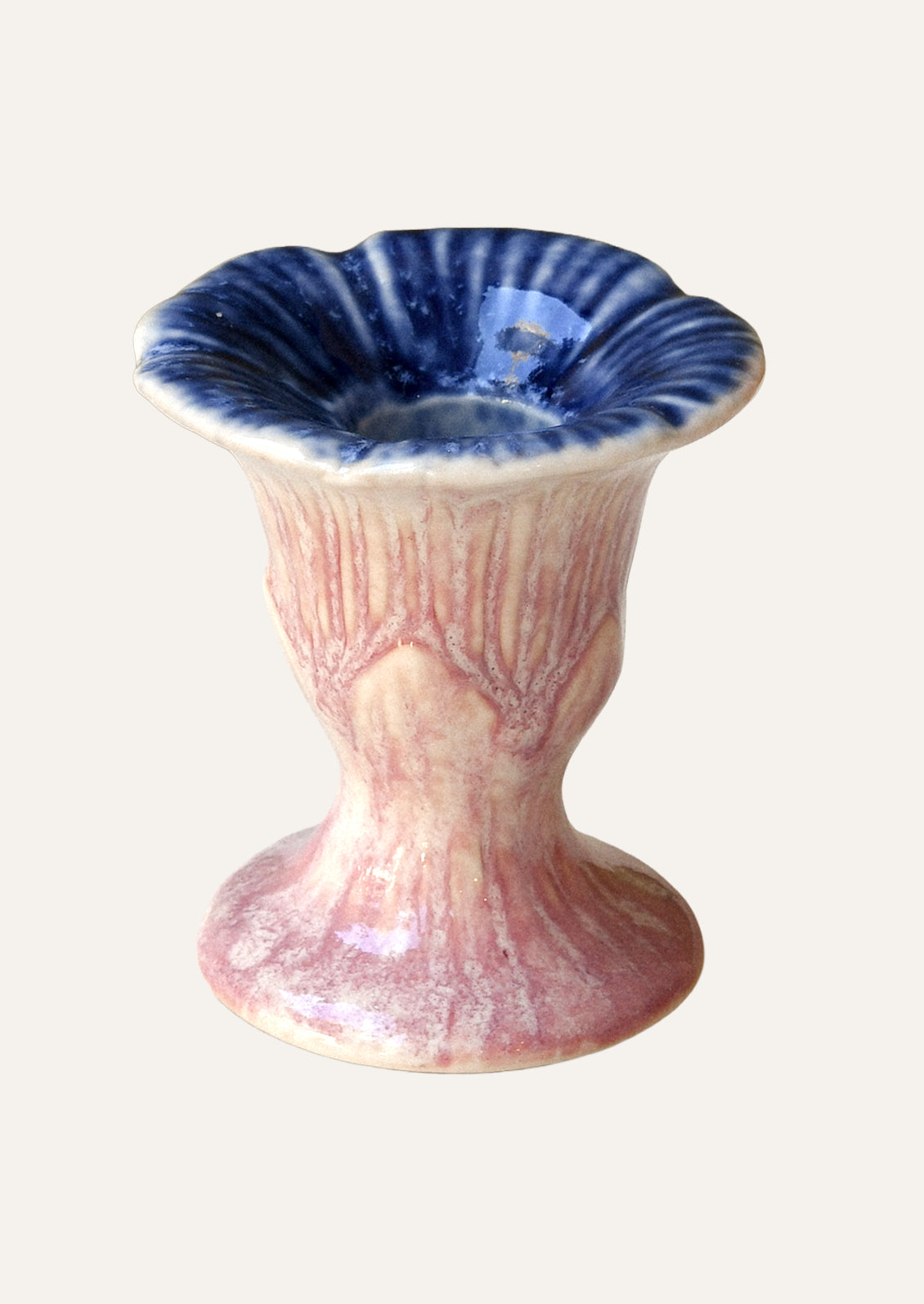 A blue and pink colored ceramic taper candle holder shaped like a flower.