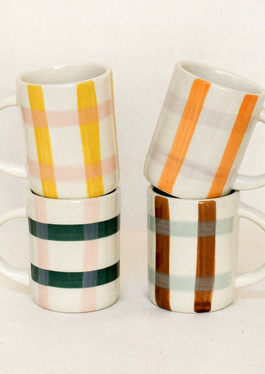 Four white ceramic mugs stacked in two pairs, each decorated with a vertical plaid stripe pattern in different colors including yellow, pink, green, orange, brown, and gray.