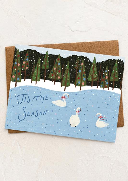 Holiday card with swans and Christmas trees on a snowy background