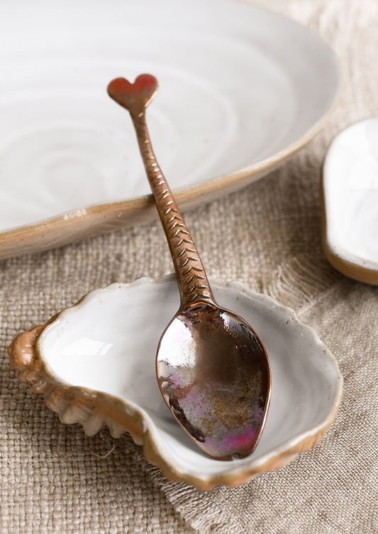 A copper spoon with fish-tail handle.