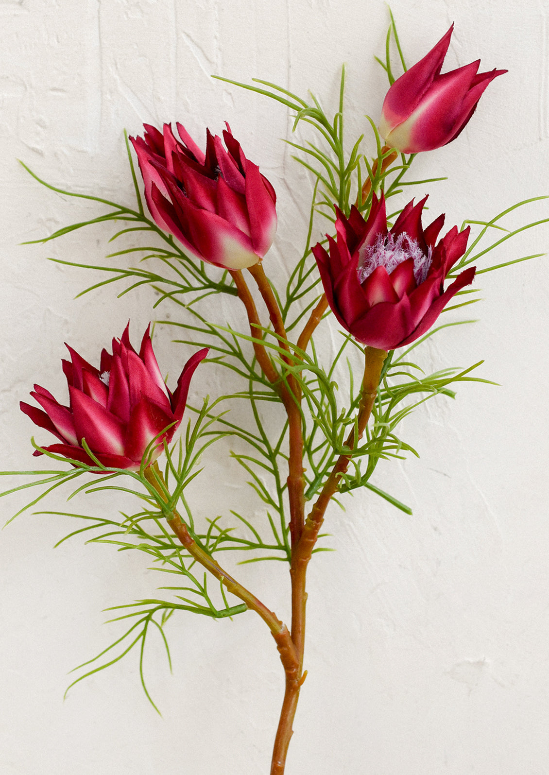 A faux flower stem depicting a protea flower in magenta.