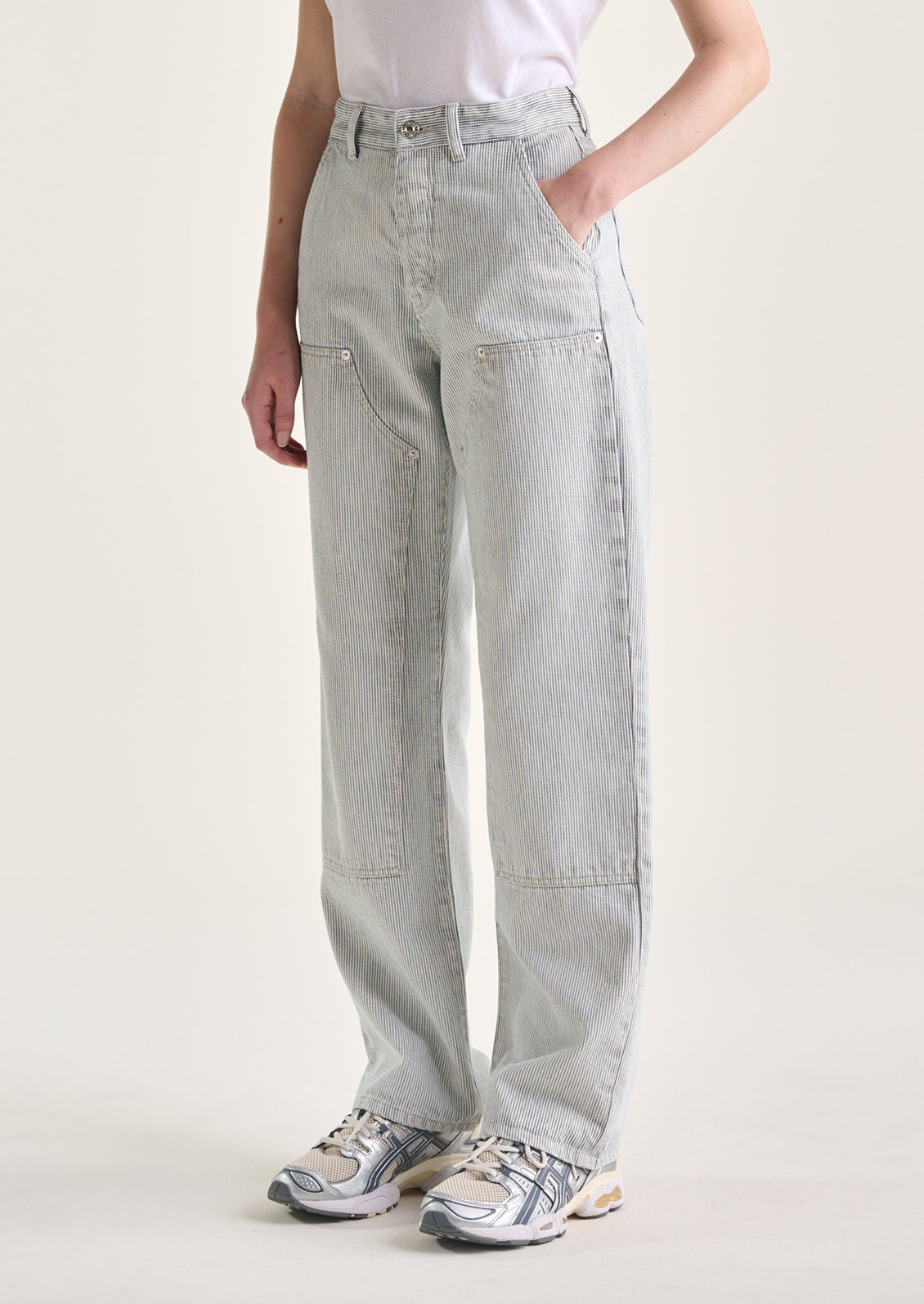 A woman wearing a pair of carpenter-style jeans in thin black pinstripe.