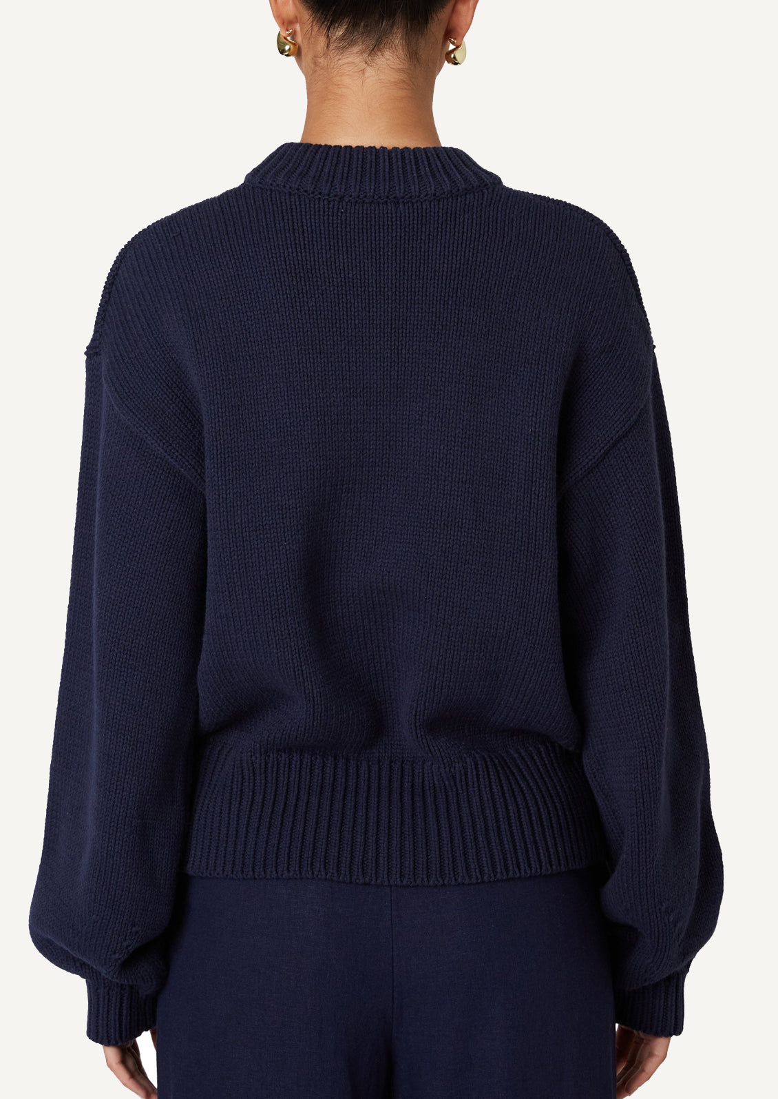 A woman wearing a crewneck sweater in navy.