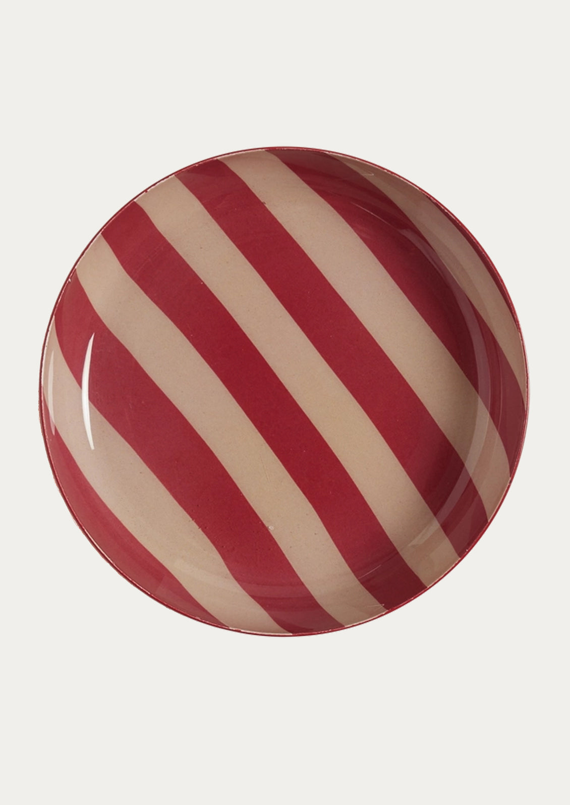 A round enamel plate featuring wide stripes in deep red and warm cream.