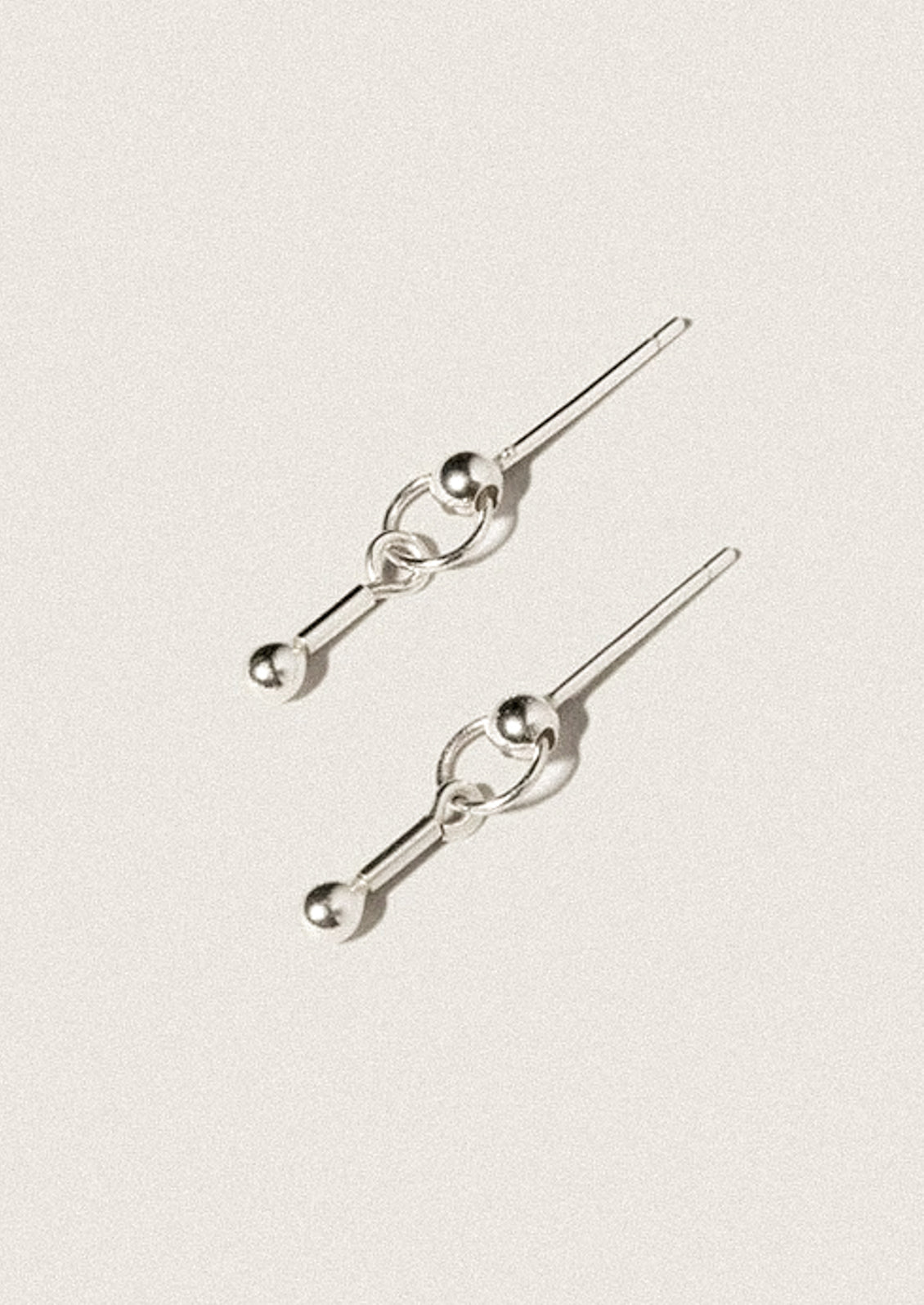 A pair of sterling silver stud earrings in dangling barbell shape.