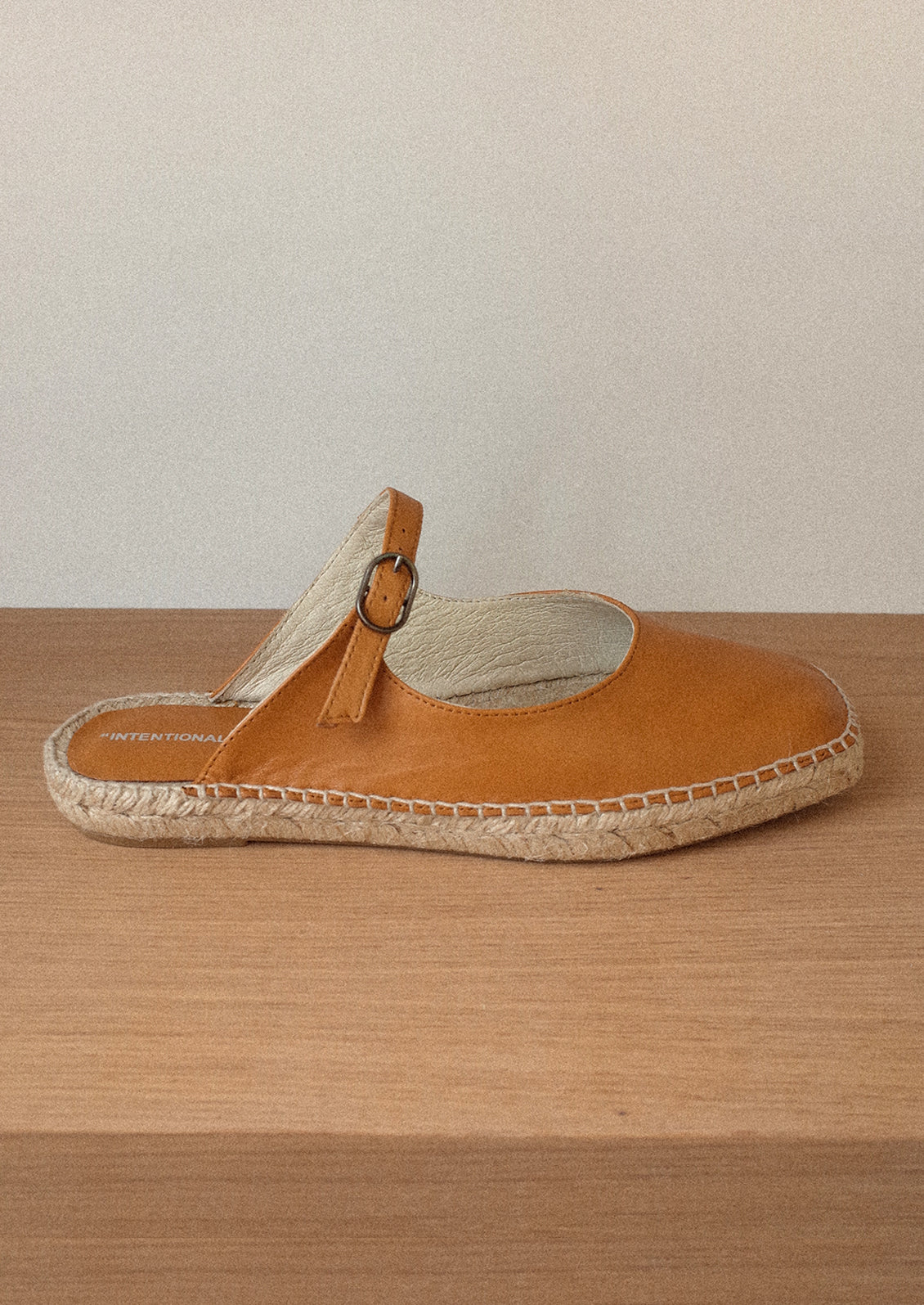 A flat mule slip on in cider brown with mary jane buckle vamp and jute sole.