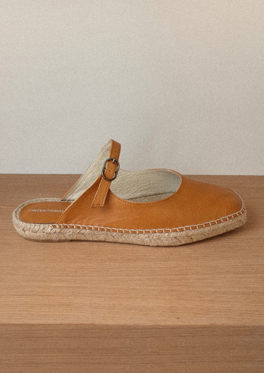 A flat mule slip on in cider brown with mary jane buckle vamp and jute sole.