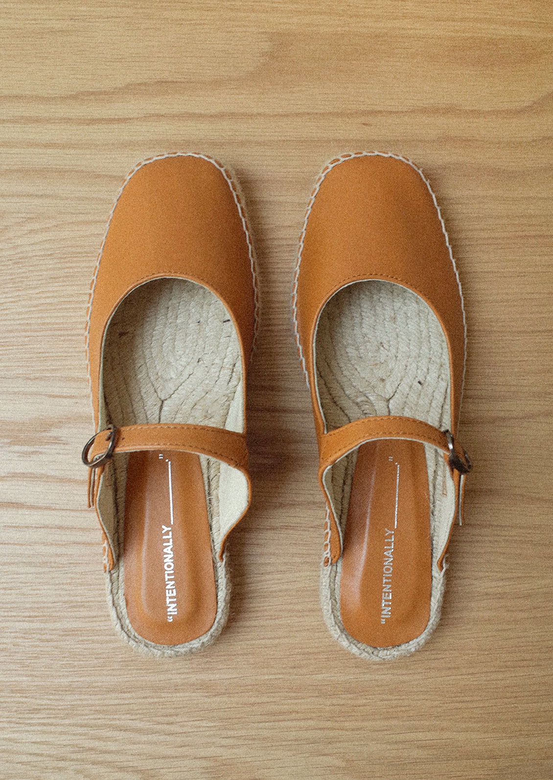 A flat mule slip on in cider brown with mary jane buckle vamp and jute sole.