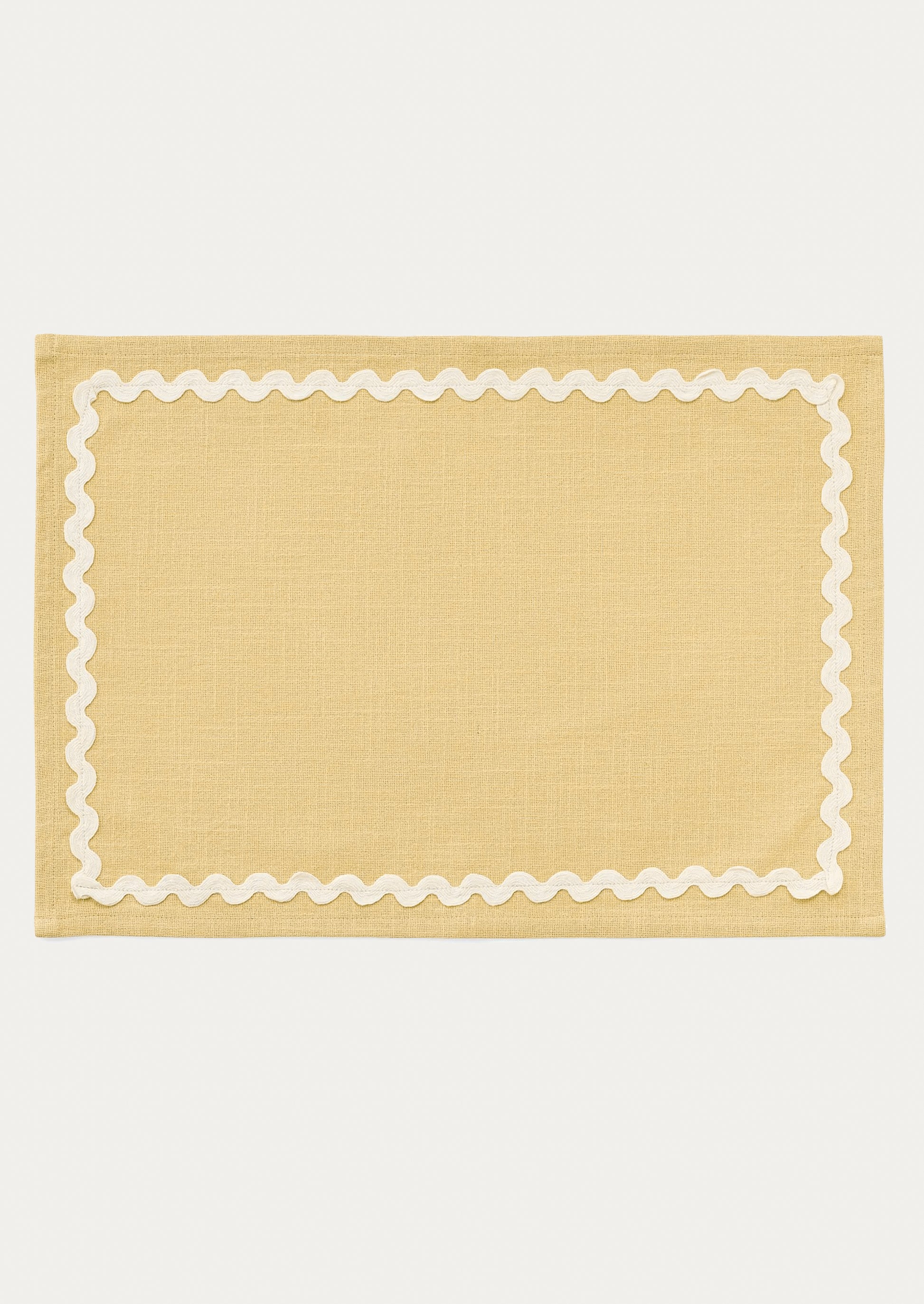 A butter yellow placemat with white ricrac trim border.
