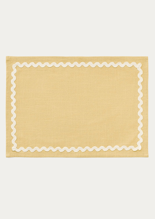 A butter yellow placemat with white ricrac trim border.