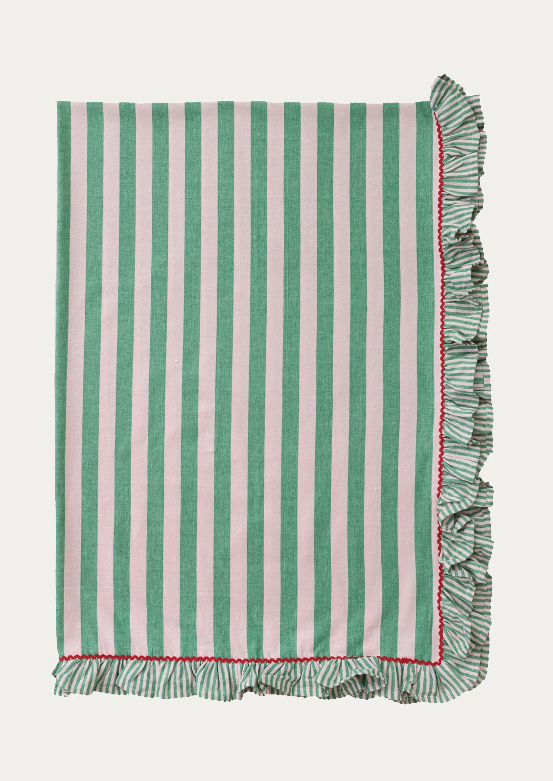 A folded tablecloth with wide blush and green stripes and red ricrac ruffle trim.