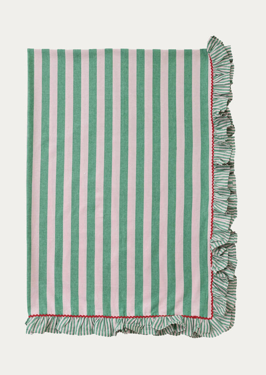 A folded tablecloth with wide blush and green stripes and red ricrac ruffle trim.