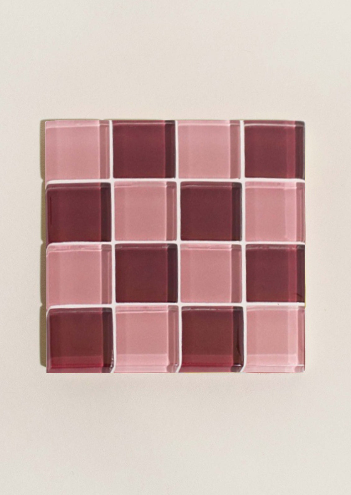 A glass tile coaster in two tone checker pattern in pink and burgundy.