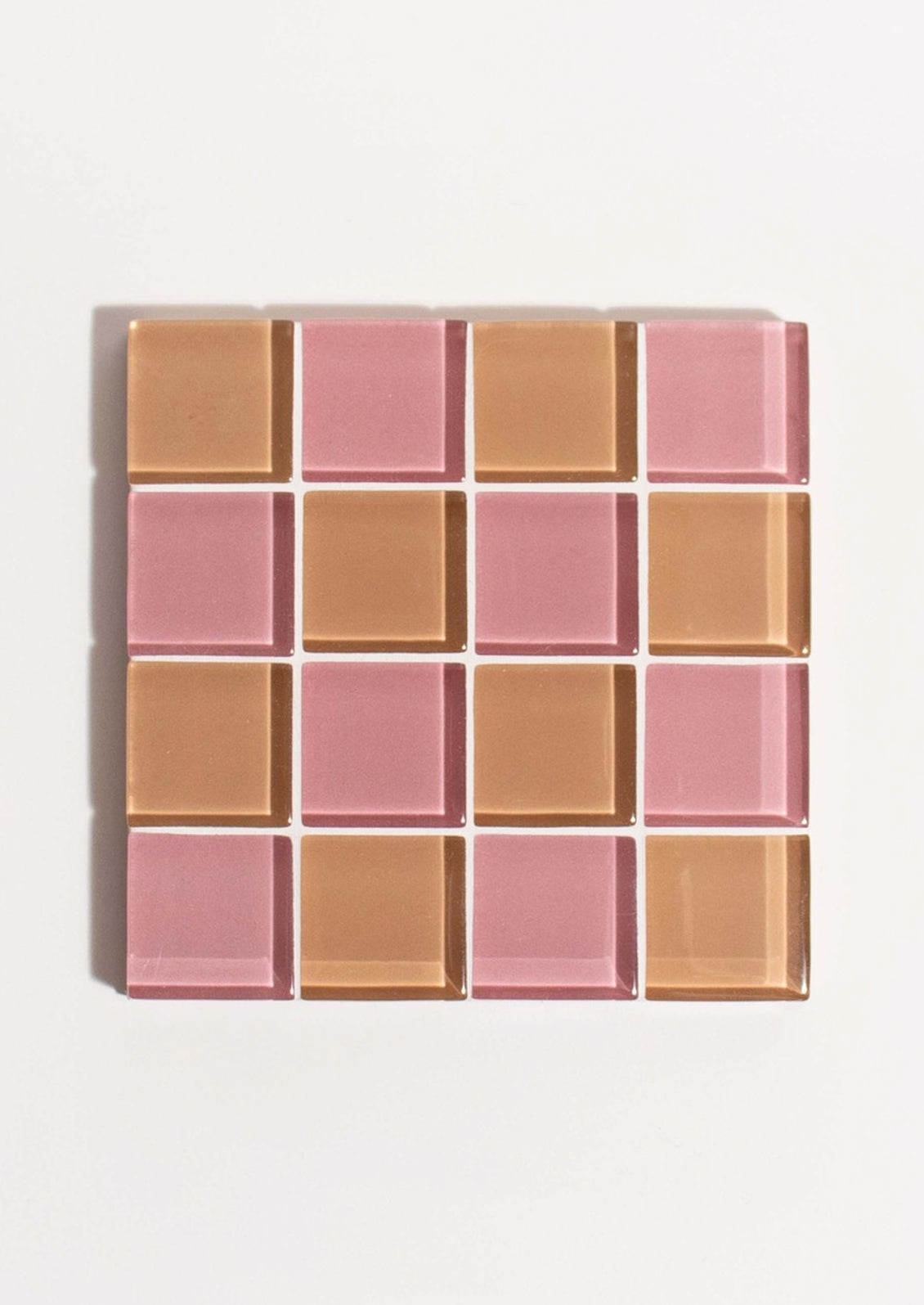 A glass tile coaster in two tone checker pattern in pink and brown.