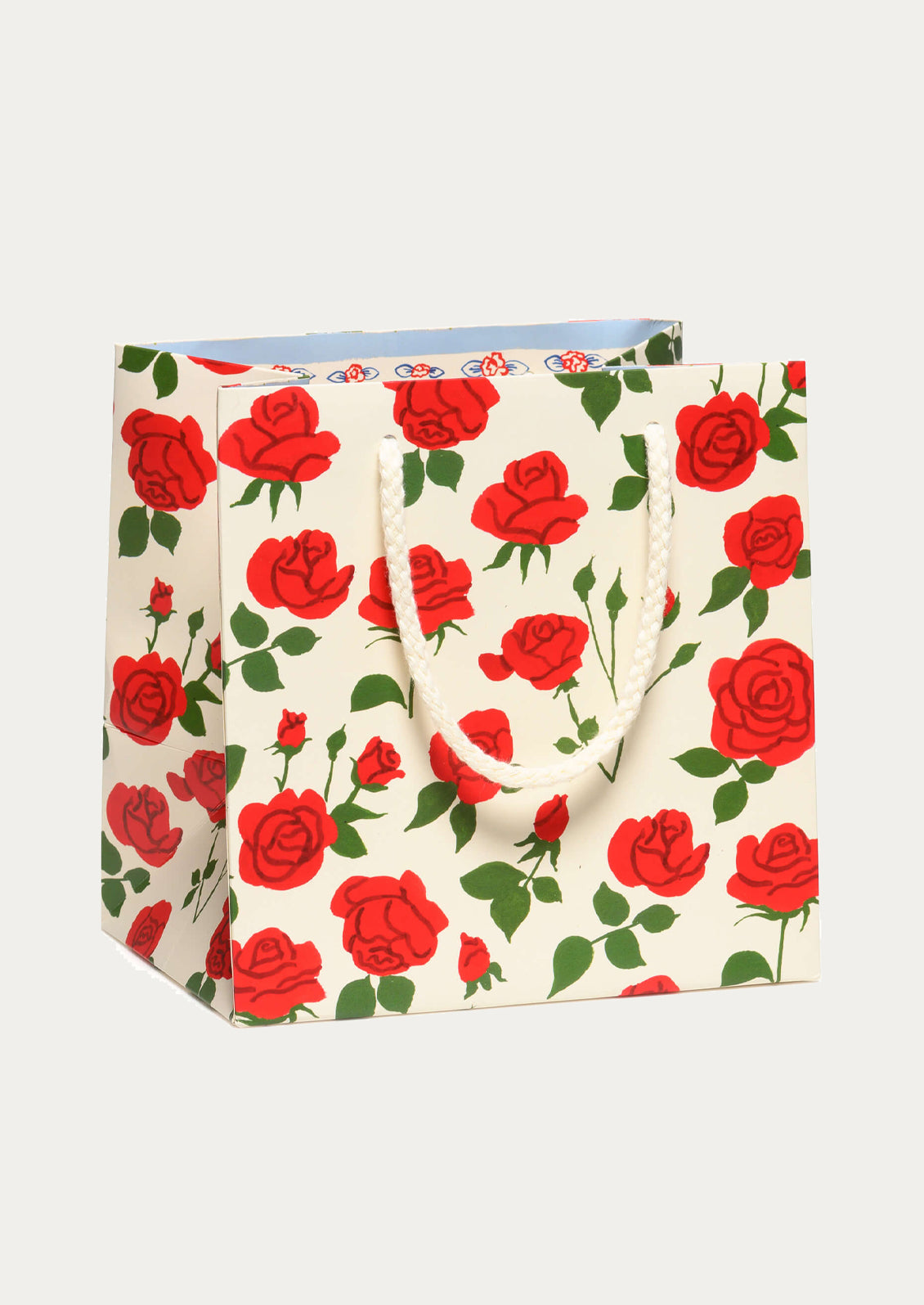 A printed gift bag with red rose pattern on white background.