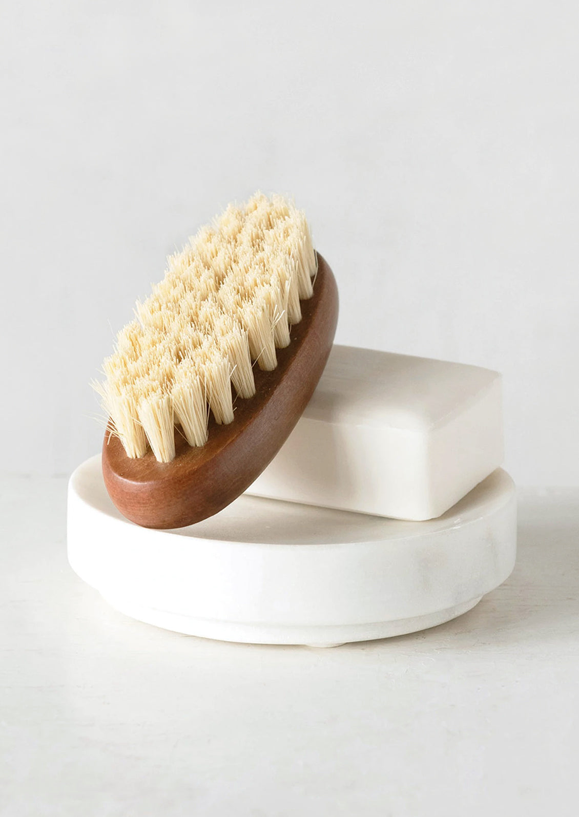 A round marble soap dish holding soap and brush.