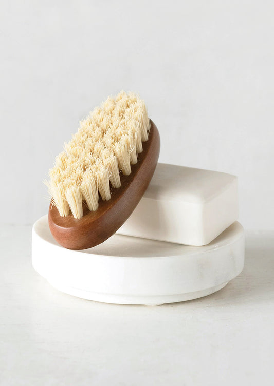 A round marble soap dish holding soap and brush.