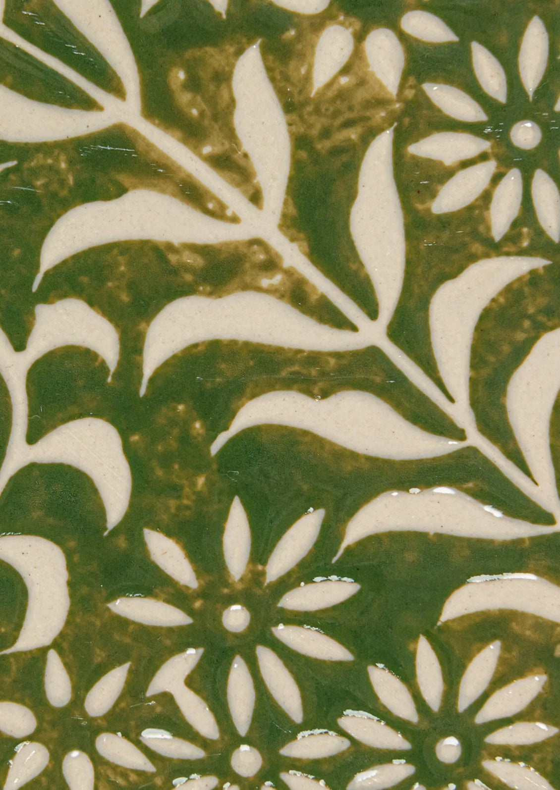 An oval shaped ceramic tray in green with botanical wax relief pattern.