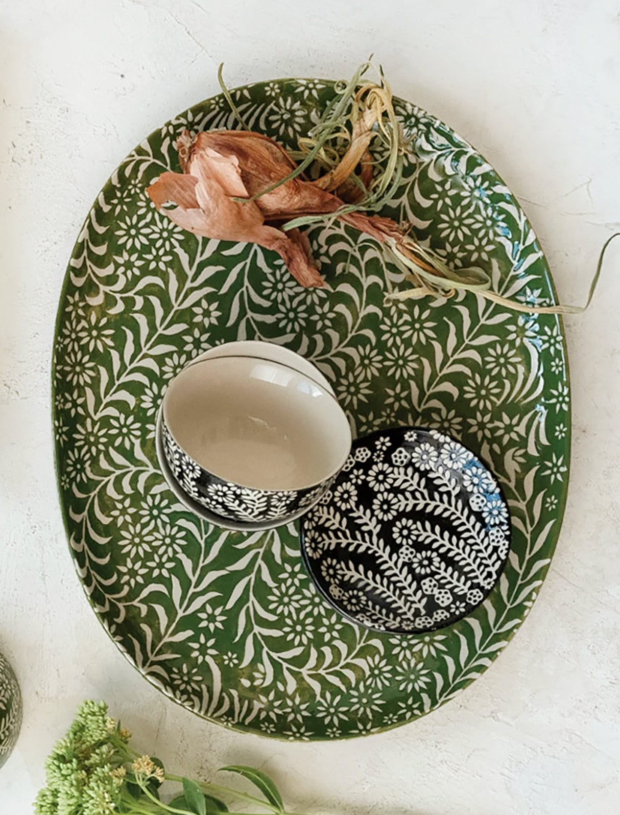 An oval shaped ceramic tray in green with botanical wax relief pattern.